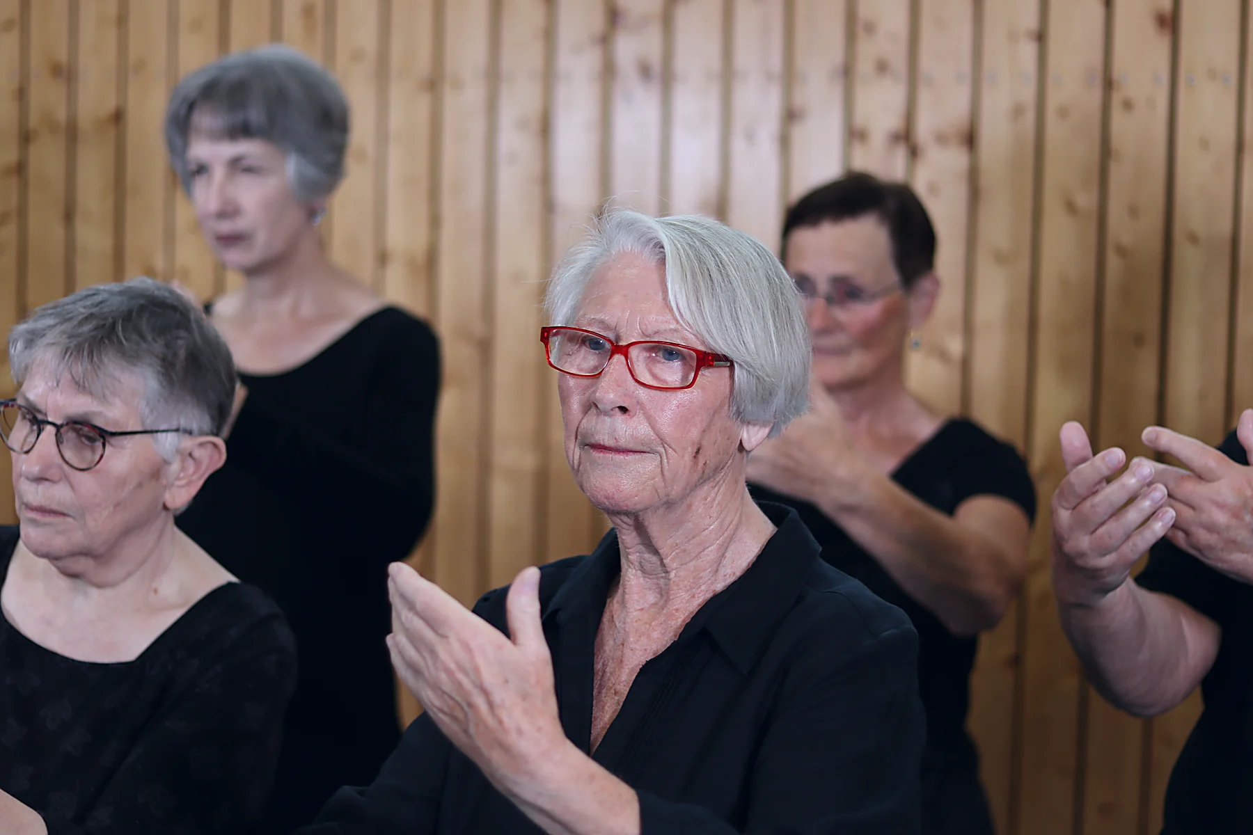 Uschi Panschar mit roter Brille führt im Qi Gong eine ruhige Handbewegung aus, hinter ihr die Gruppe