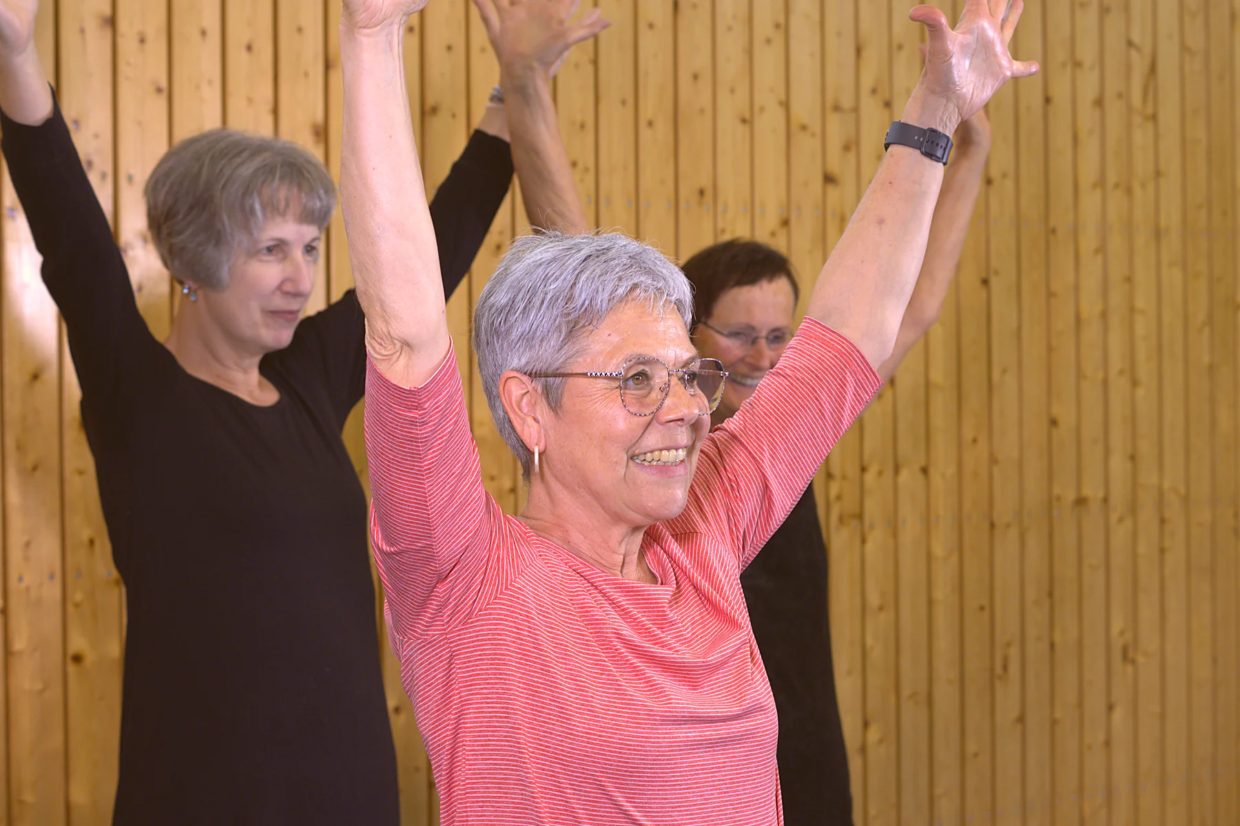 Martina streckt im Rückenfit-Kurs lachend die Arme nach oben, hinter ihr die Gruppe