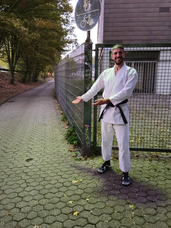 Schmaler Weg zwischen Zaun und Straße am Schild für Fuß- und Radweg