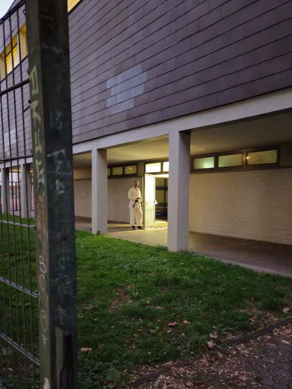 Blick durch den überdachten Gang auf die offene Tür der Halle